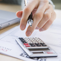 A man's hand using calculator to make financial decisions.