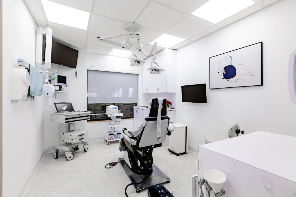 Advanced dental procedure room with multiple treatment chairs, wall-mounted displays, surgical lighting, comprehensive clinical equipment, and skylight