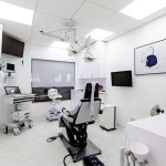 Advanced dental procedure room with multiple treatment chairs, wall-mounted displays, surgical lighting, comprehensive clinical equipment, and skylight