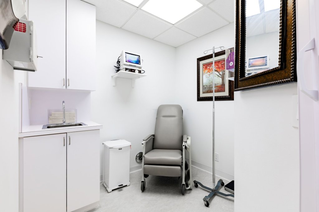 Compact dental operatory with grey patient chair, white cabinetry, wall-mounted equipment, mirror, and skylight in clean modern design